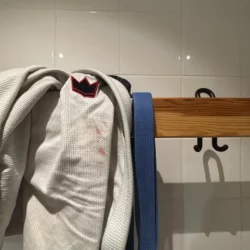Kimono blanc AAM De La Riva avec logo rouge, présenté sur cintre en bois