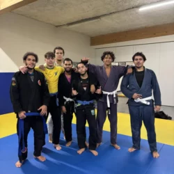 Groupe de praticiens en gis noir, blanc et bleu alignés sur le tatami du club
