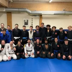 Groupe de praticiens en gis noir, blanc et bleu alignés sur le tatami du club
