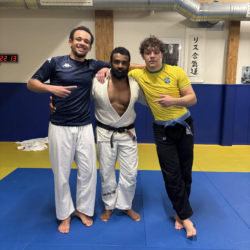 Groupe de praticiens en gis noir, blanc et bleu alignés sur le tatami du club